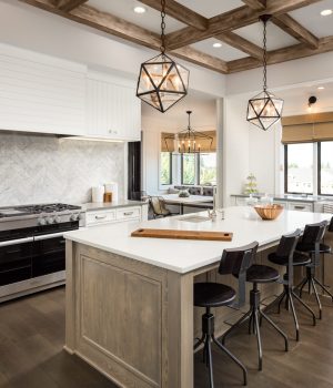 Kitchen Interior with Island, Sink, Cabinets, and Hardwood Floors in New Luxury Home. Includes elegant pendant light fixtures and wood beam ceiling
